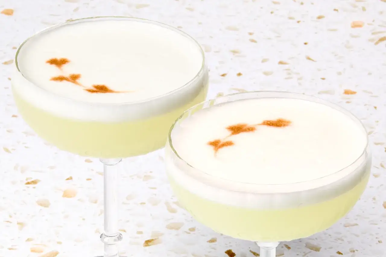 Två vackra Pisco Sour-drinkar med ett dekorativt mönster på skummet. Perfekt för ett pisco sour recept.