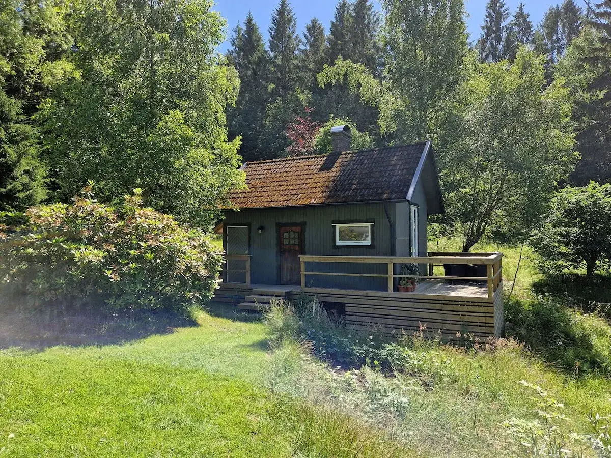 En mysig stuga vid Hyssna Forest Resort, omgiven av grönskande träd och en vacker trädgård.