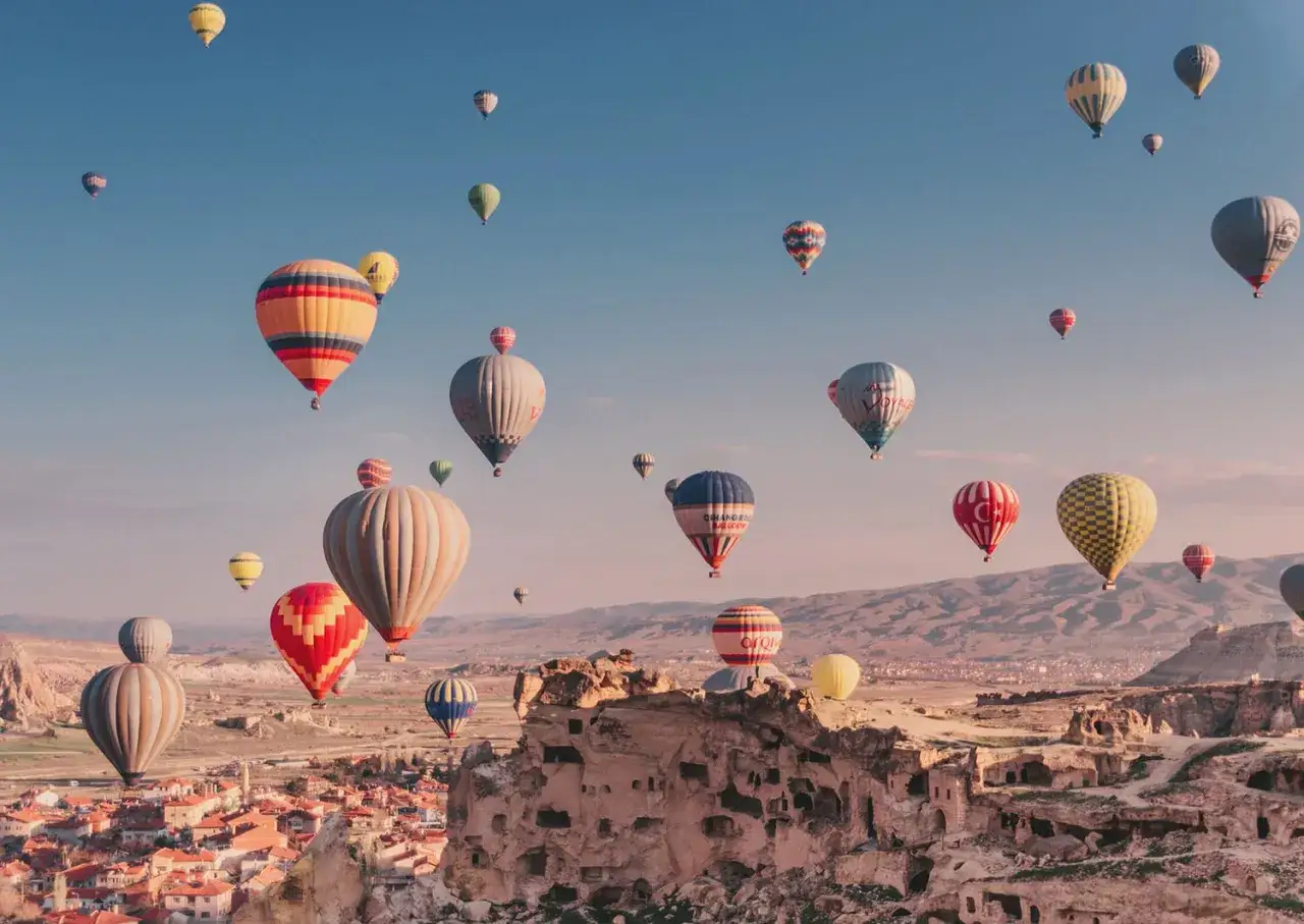 Många färgglada luftballonger svävar över Cappadocias unika landskap i Turkiet. En magisk luftballong turkiet-upplevelse.