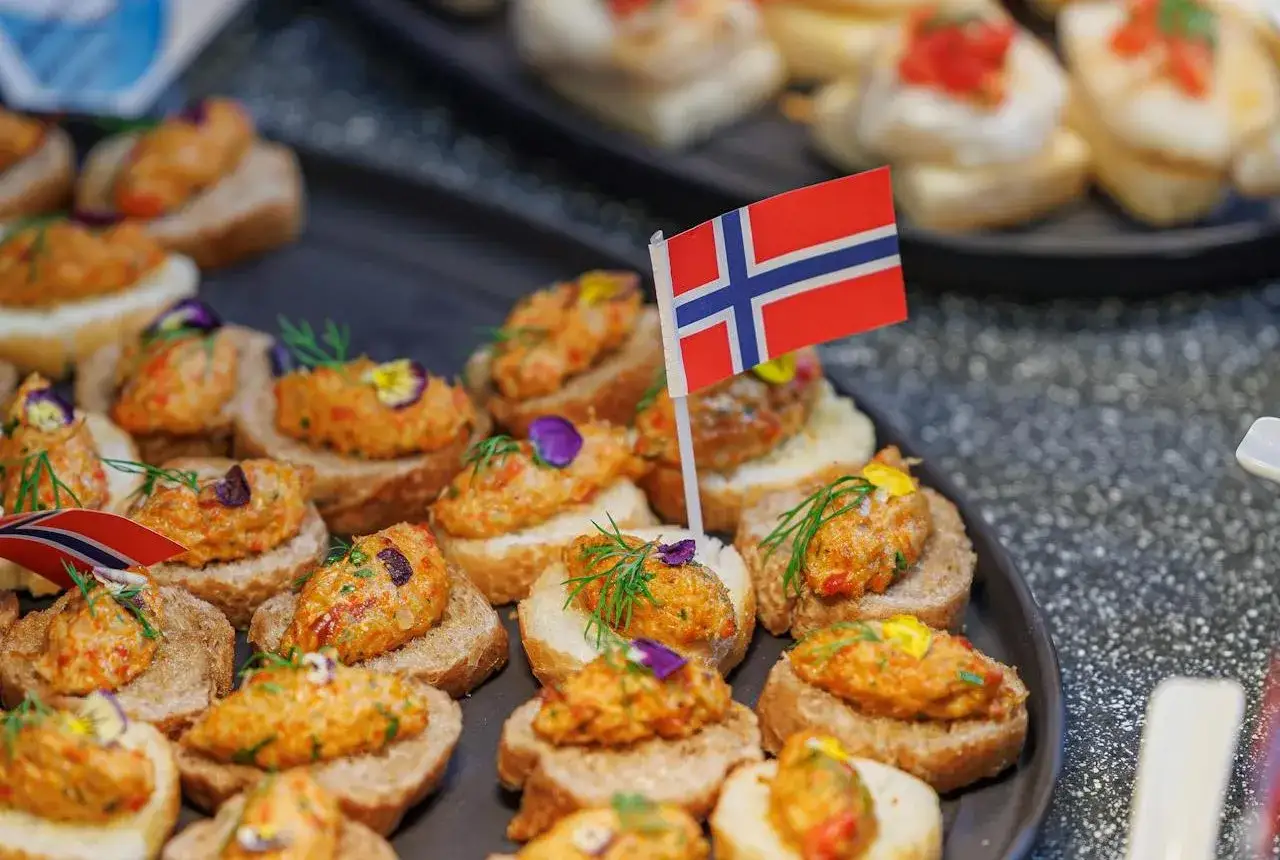 Små snittar med röra och örter, dekorerade med norska flaggor. En smak av norsk mat som ser utsökt ut.