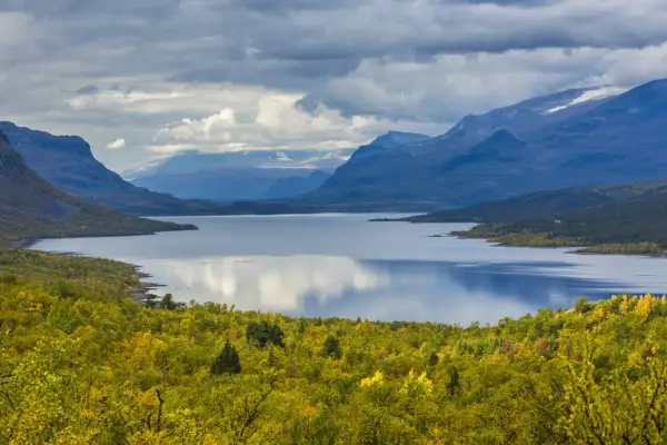 Vacker sjö omgiven av höstfärgad skog och berg. Perfekt för vandring dagsturer Sverige.